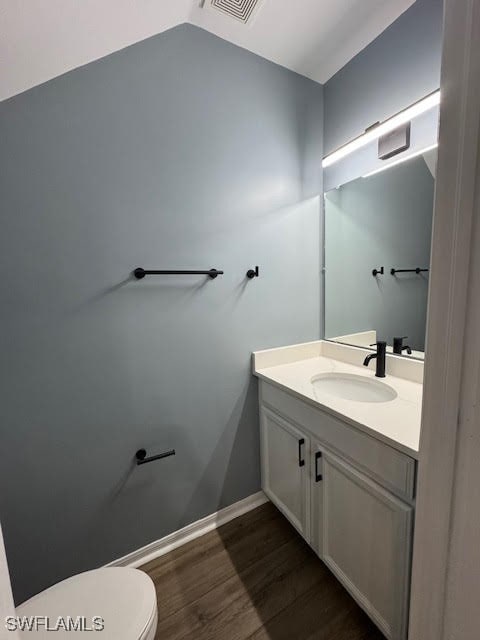 bathroom with vanity, toilet, vaulted ceiling, and hardwood / wood-style floors