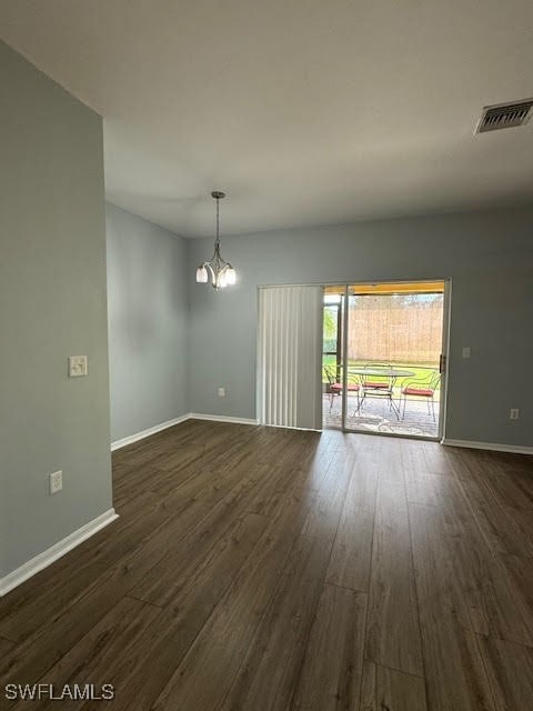 spare room featuring a chandelier and dark hardwood / wood-style floors