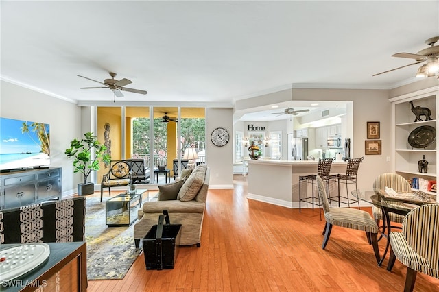 living room with ornamental molding, wood-type flooring, and ceiling fan