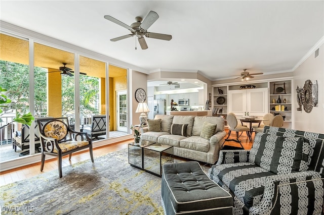 living room with ceiling fan, ornamental molding, and wood-type flooring