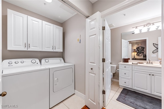 clothes washing area with light tile patterned floors, cabinets, washer and clothes dryer, and sink