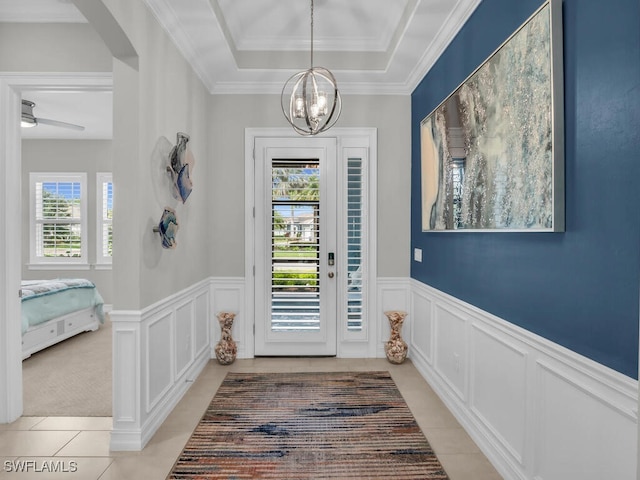 tiled entrance foyer featuring ornamental molding, an inviting chandelier, and a raised ceiling