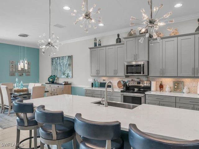 kitchen with appliances with stainless steel finishes, tasteful backsplash, a chandelier, gray cabinetry, and pendant lighting