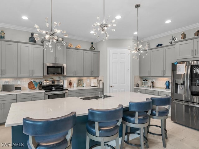 kitchen with sink, decorative light fixtures, tasteful backsplash, a kitchen island with sink, and stainless steel appliances