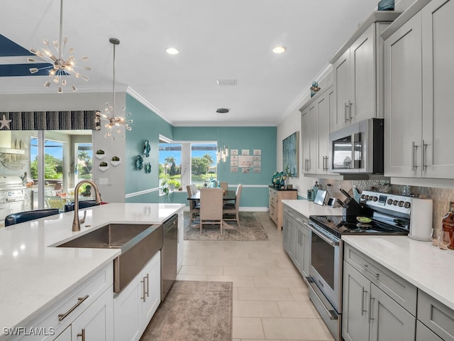 kitchen with sink, backsplash, gray cabinets, an inviting chandelier, and stainless steel appliances