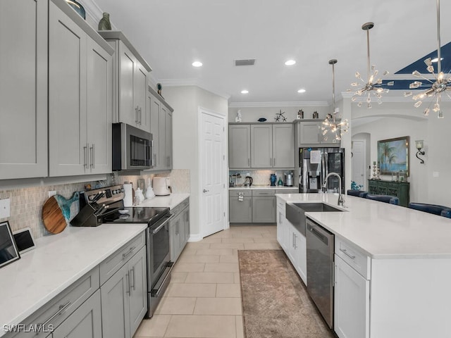 kitchen featuring stainless steel appliances, an island with sink, decorative backsplash, sink, and light tile patterned floors