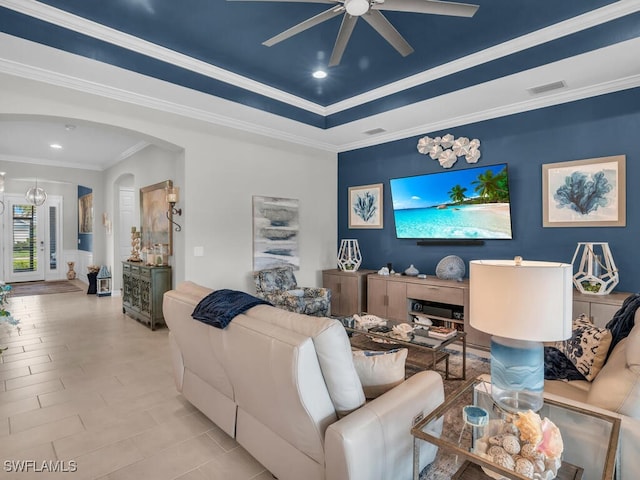 living room with a tray ceiling, ceiling fan, and ornamental molding