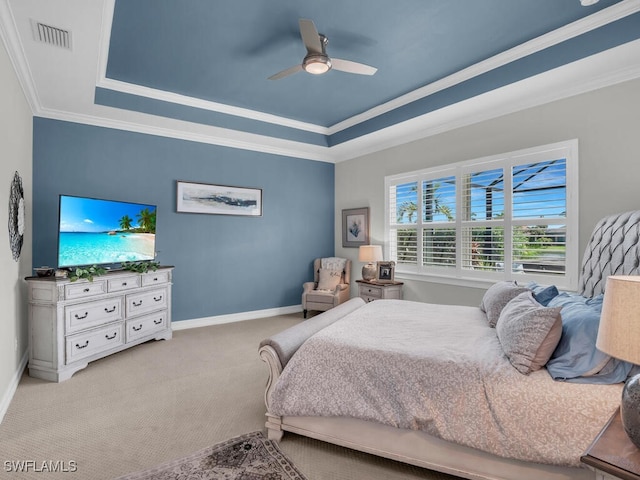 carpeted bedroom with ceiling fan, a tray ceiling, and ornamental molding