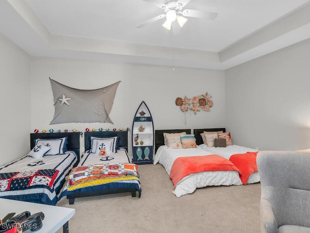 carpeted bedroom featuring ceiling fan and a raised ceiling