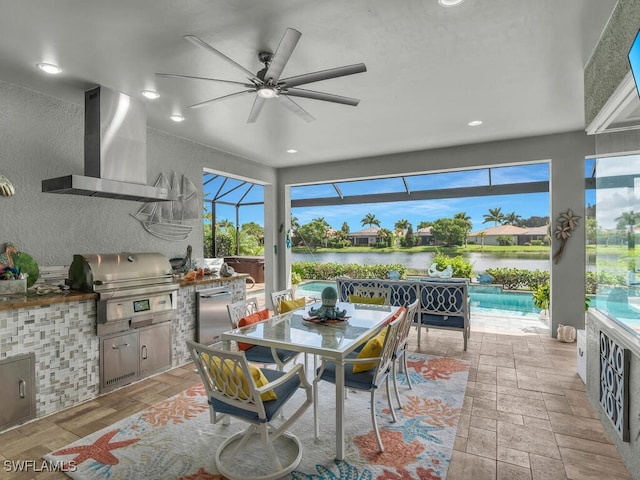 view of patio / terrace with glass enclosure, a water view, exterior kitchen, a grill, and ceiling fan