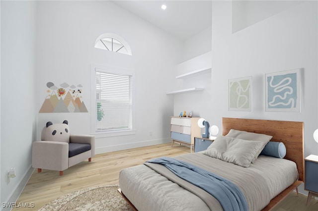 bedroom featuring light wood-type flooring, multiple windows, and high vaulted ceiling