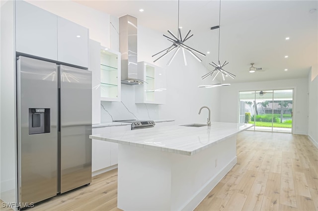 kitchen with a kitchen island with sink, sink, appliances with stainless steel finishes, white cabinets, and light hardwood / wood-style floors