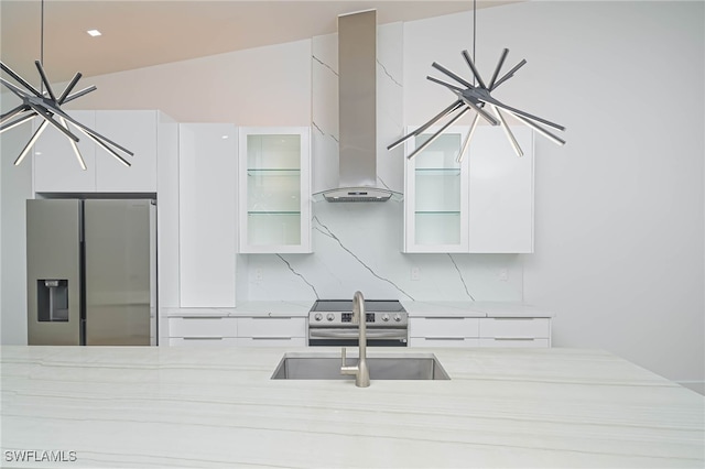 kitchen featuring white cabinetry, stainless steel appliances, vaulted ceiling, decorative backsplash, and wall chimney exhaust hood