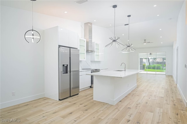 kitchen with white cabinets, pendant lighting, stainless steel appliances, and wall chimney exhaust hood