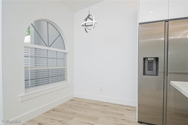 kitchen featuring light wood-type flooring, white cabinets, stainless steel fridge, and pendant lighting