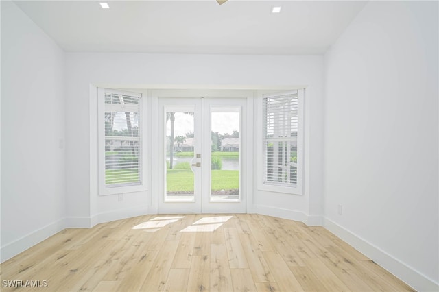 doorway with a healthy amount of sunlight, light wood-type flooring, and french doors