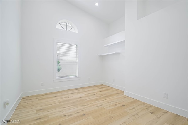 unfurnished room featuring high vaulted ceiling, a healthy amount of sunlight, and light hardwood / wood-style flooring