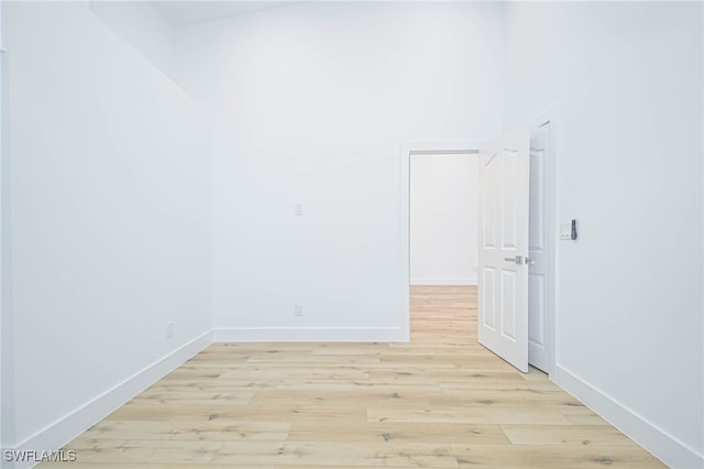 spare room featuring a towering ceiling and light hardwood / wood-style flooring