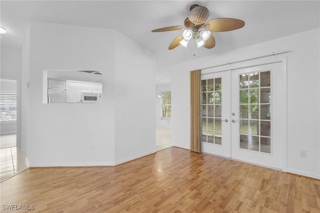 unfurnished living room with ceiling fan, vaulted ceiling, french doors, and light hardwood / wood-style floors