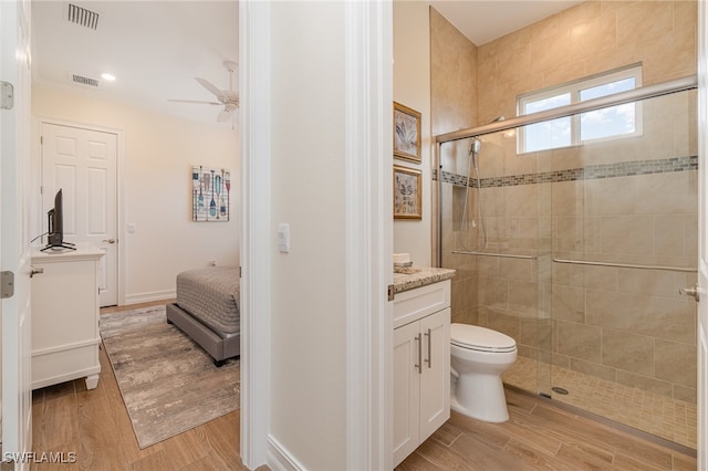 bathroom with ceiling fan, hardwood / wood-style floors, an enclosed shower, toilet, and vanity