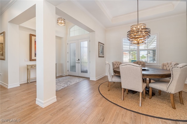 dining area featuring french doors, a raised ceiling, crown molding, a chandelier, and light wood-type flooring