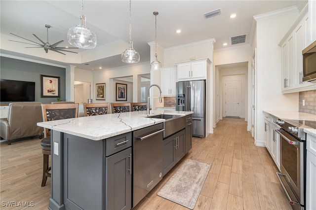 kitchen featuring decorative backsplash, white cabinetry, a kitchen island with sink, and appliances with stainless steel finishes