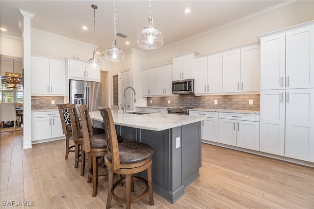 kitchen with white cabinets, decorative light fixtures, sink, and appliances with stainless steel finishes