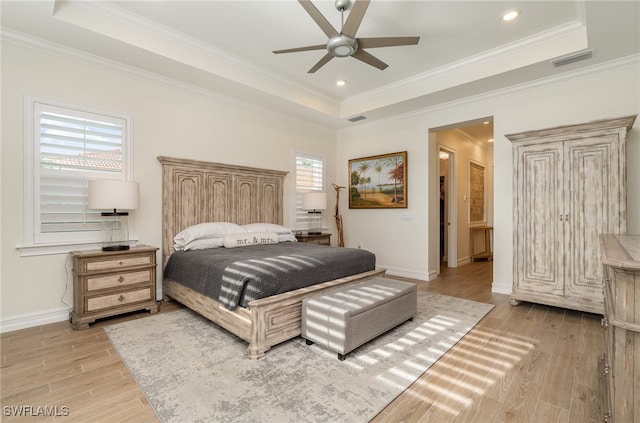 bedroom featuring a tray ceiling, ceiling fan, light hardwood / wood-style flooring, and crown molding