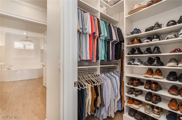 spacious closet featuring hardwood / wood-style floors and an inviting chandelier