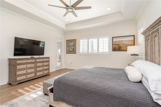 bedroom featuring light wood-type flooring, a raised ceiling, ceiling fan, and crown molding