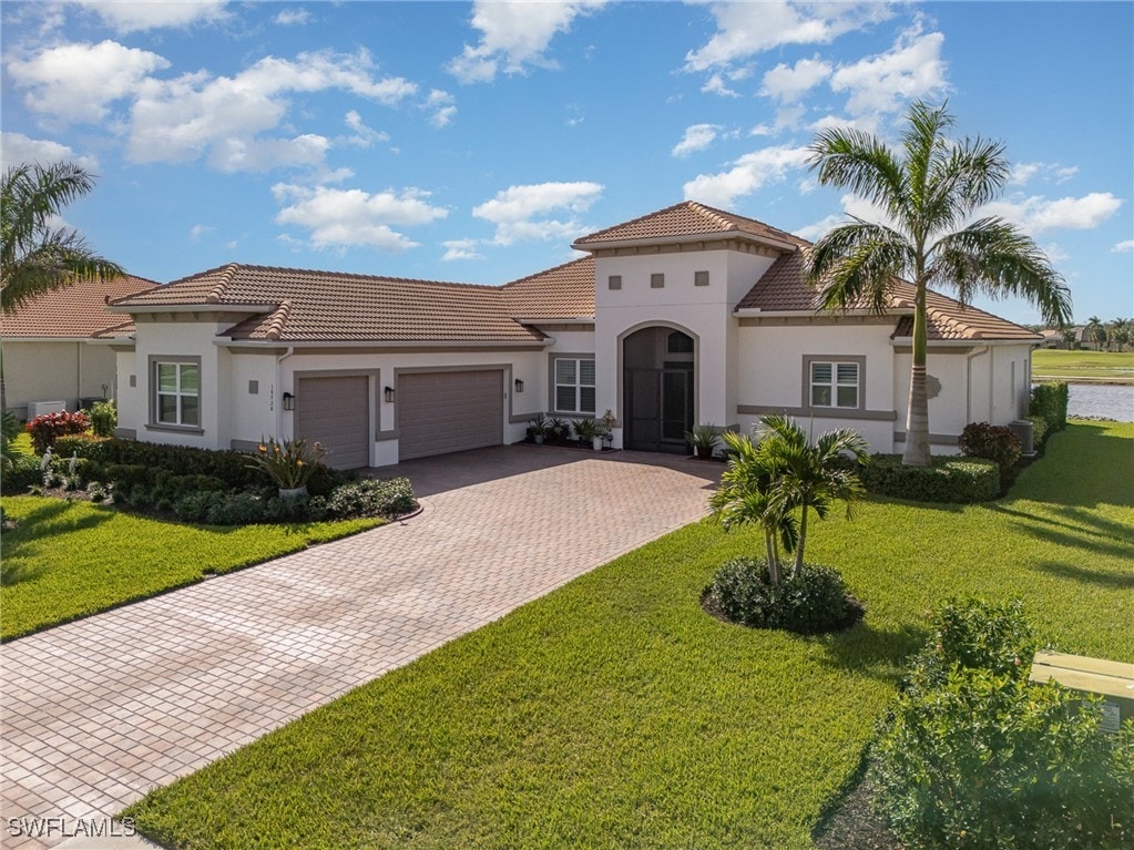 mediterranean / spanish-style house with a garage and a front lawn