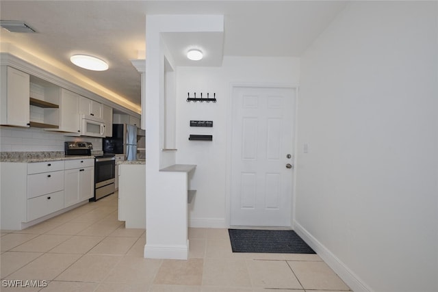 kitchen featuring white cabinets, appliances with stainless steel finishes, backsplash, and light tile patterned floors