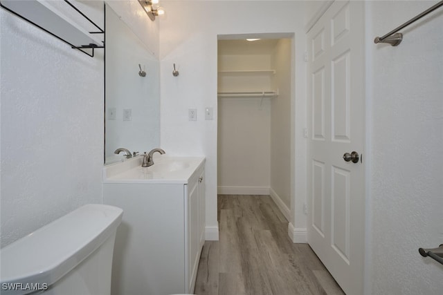 bathroom featuring wood-type flooring, vanity, and toilet