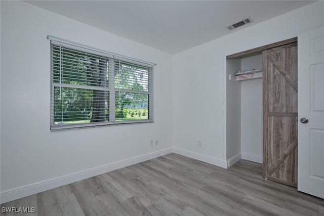 unfurnished bedroom with light wood-type flooring and a closet