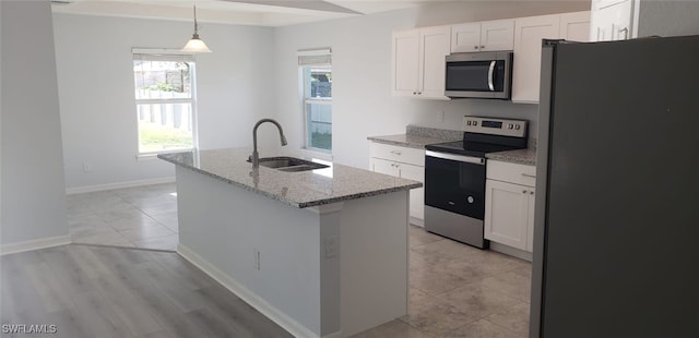 kitchen featuring pendant lighting, appliances with stainless steel finishes, an island with sink, sink, and white cabinets