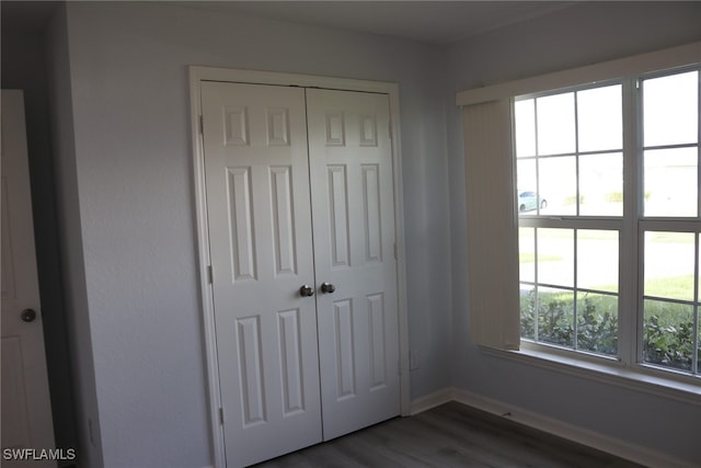 unfurnished bedroom with dark wood-type flooring and a closet