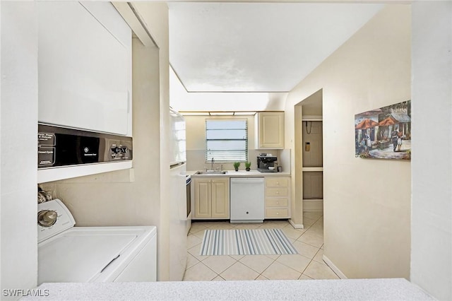 kitchen with dishwasher, cream cabinets, sink, light tile patterned floors, and washer / dryer