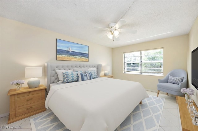 bedroom featuring ceiling fan, light tile patterned floors, and a textured ceiling