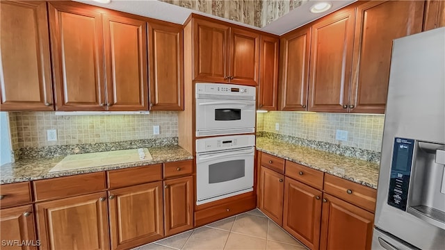 kitchen with white appliances, light stone countertops, light tile patterned floors, and decorative backsplash