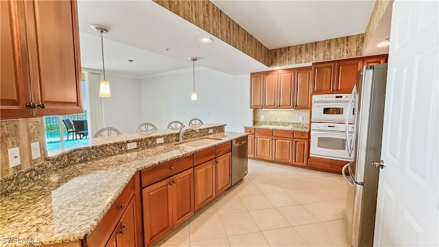 kitchen featuring light stone countertops, pendant lighting, sink, and stainless steel appliances