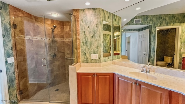 bathroom featuring an enclosed shower, vanity, and toilet