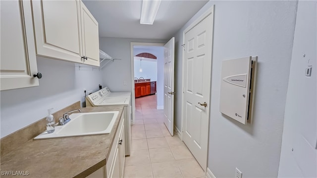 laundry area with washing machine and dryer, cabinets, sink, and light tile patterned flooring