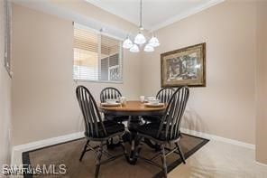 dining area featuring crown molding, carpet floors, and a chandelier