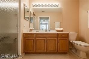 bathroom featuring a shower with shower door, toilet, and vanity