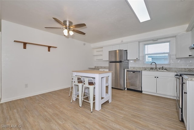 kitchen featuring white cabinetry, appliances with stainless steel finishes, sink, and light hardwood / wood-style flooring