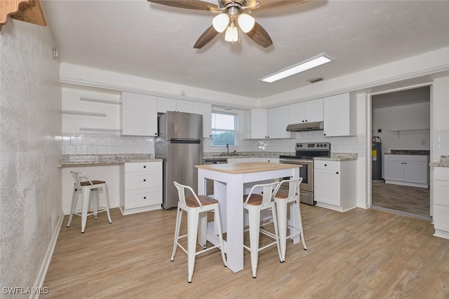 kitchen featuring stainless steel appliances, light wood-type flooring, a breakfast bar, white cabinets, and ceiling fan