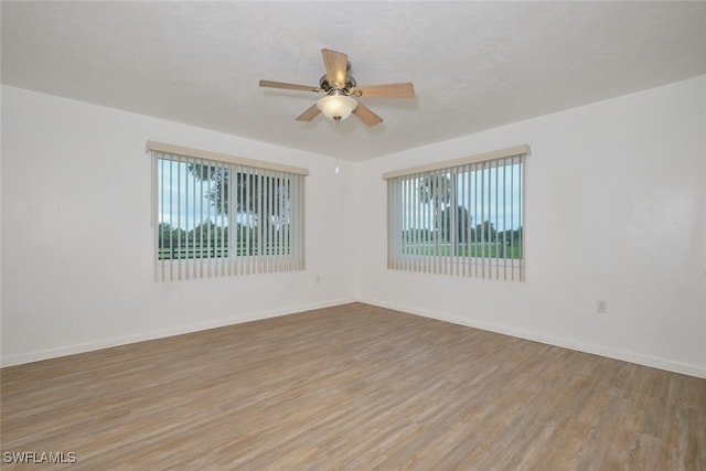 spare room featuring light wood-type flooring, ceiling fan, and plenty of natural light