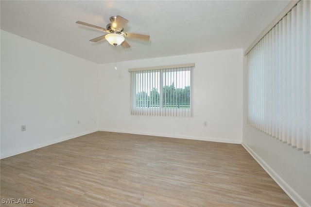 empty room with ceiling fan and light hardwood / wood-style flooring