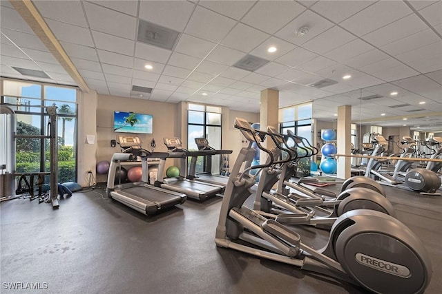 gym featuring a drop ceiling, plenty of natural light, and floor to ceiling windows