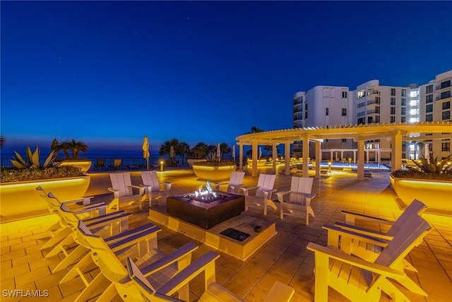 patio at night featuring an outdoor fire pit and a pergola